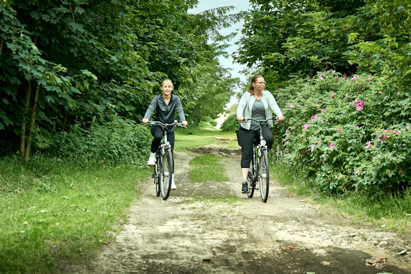 Zwei entgegenkommende Radfahrerinnen auf einem Waldweg