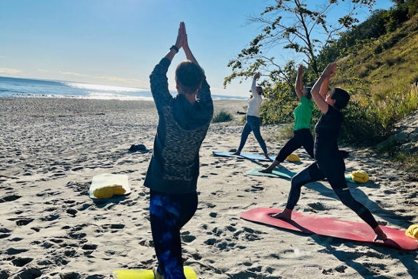 Rehabilitanden beim Yoga vor blauem Himmel und der Ostsee